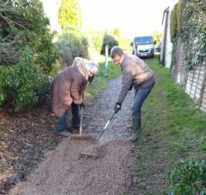 Volunteers rake a footpath